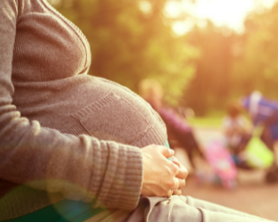 Photo of a pregnant woman sitting on a bench at a park